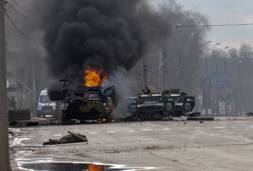 ▲지난달 27일(현지시간) 우크라이나 하르키우에서 러시아군 병력수송 장갑차(왼쪽)가 불타고 있고 그 앞에 생사를 알 수 없는 한 군인이 쓰러져 있다. (하르키우/AP뉴시스 )