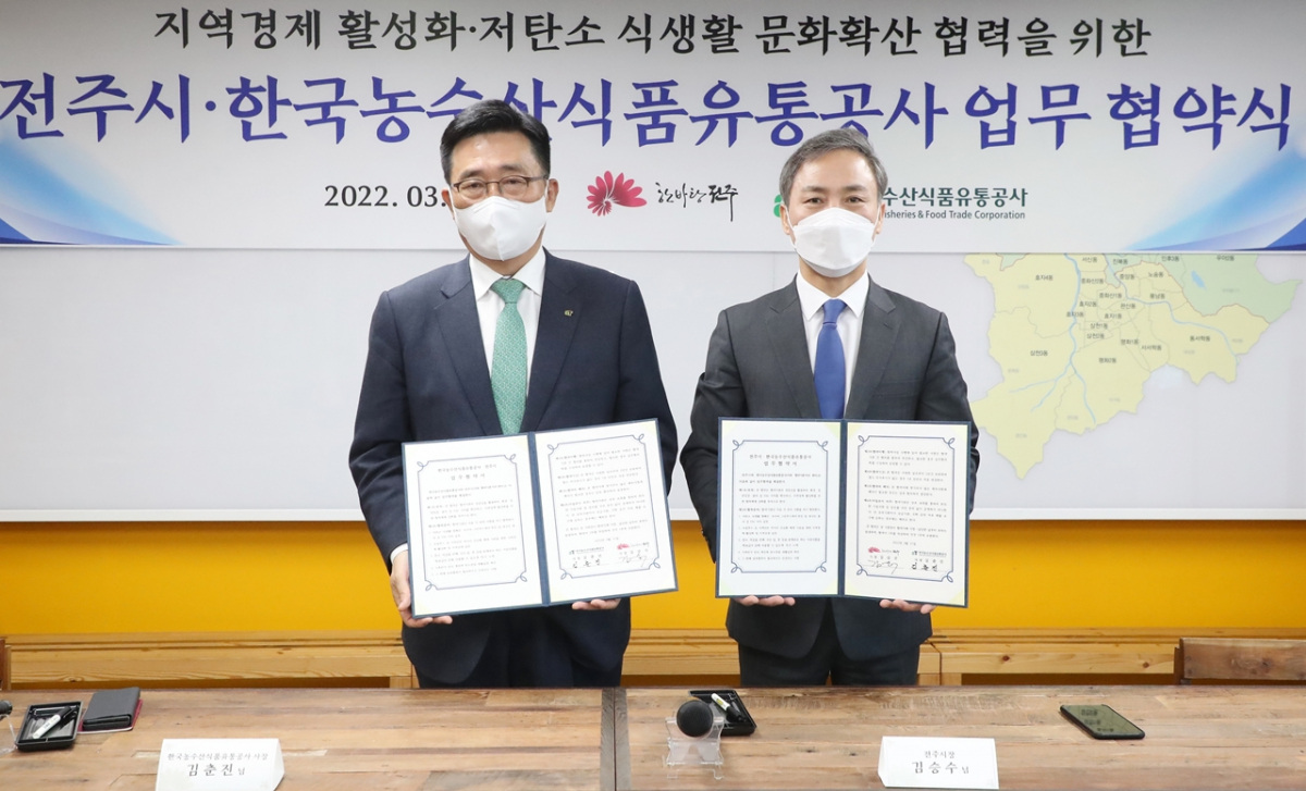 ▲김춘진 한국농수산식품유통공사(aT) 사장(왼쪽)과 김승수 전주시장이 21일 저탄소 식생활 확산 및 지역경제 활성화를 위한 업무협약을 체결하고 있다. (사진제공=한국농수산식품유통공사(aT))