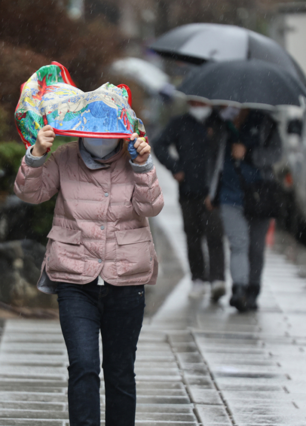 ▲14일 오후 한 시민이 비를 피하며 서울 종로구 한 거리를 지나고 있다. (연합뉴스)