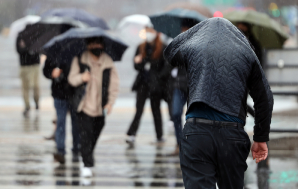 ▲14일 오후 한 시민이 옷으로 비를 피하며 서울 광화문 사거리를 지나고 있다. (연합뉴스)