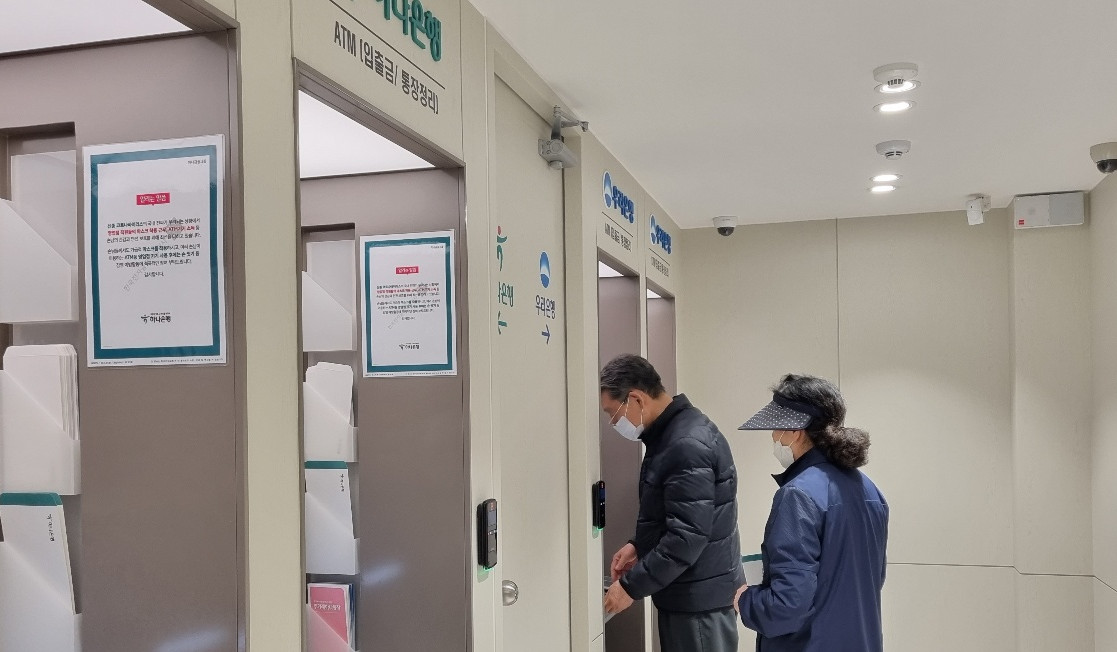 ▲이날 공동점포를 찾은 한 부부의 모습. 왼쪽에는 하나은행이 제공하는 ATM기 두 대가, 오른쪽에는 우리은행이 제공하는 ATM 두 대가 자리하고 있다. (박소은 기자 gogumee@)