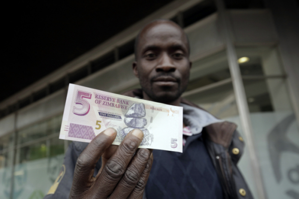 ▲짐바브웨 수도 하라레에서 한 시민이 짐바브웨 5달러 지폐를 들고 있다. 하라레/AP뉴시스