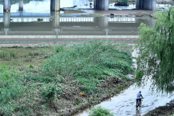 ▲위험홍수위 아래로 떨어진 서울 구로구 안양천변에서 한 시민이 자전거를 타고 있다.(이투데이DB)