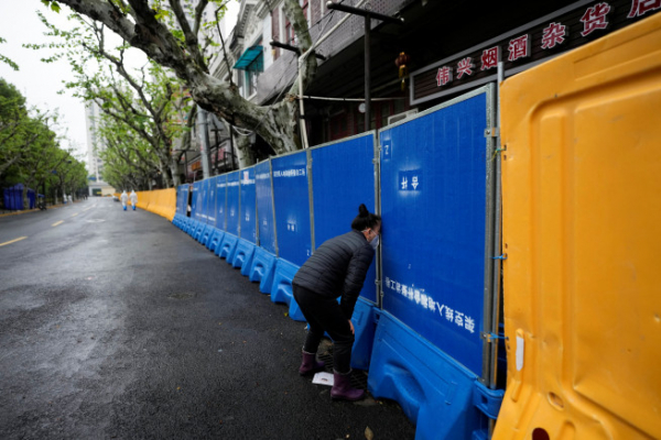 ▲중국 상하이의 신종 코로나바이러스 감염증(코로나19) 봉쇄 지역에서 14일 한 여성이 '코로나 차단벽' 사이로 노점상에게 음식을 주문하고 있다.  상하이/로이터연합뉴스