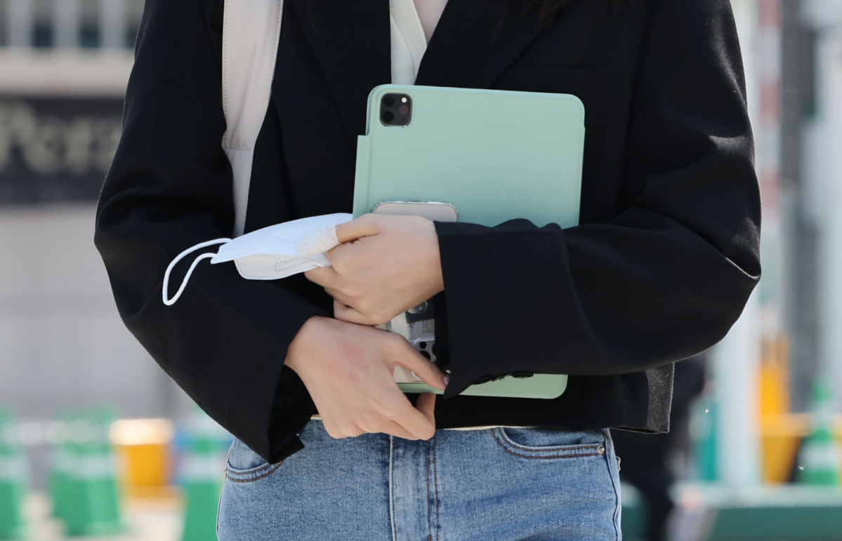 ▲실외 마스크 착용 의무화 해제 이틀째인 3일 서울 마포구 이화여자대학교에서 학생이 마스크를 손에 들고 이동하고 있다. (연합뉴스)