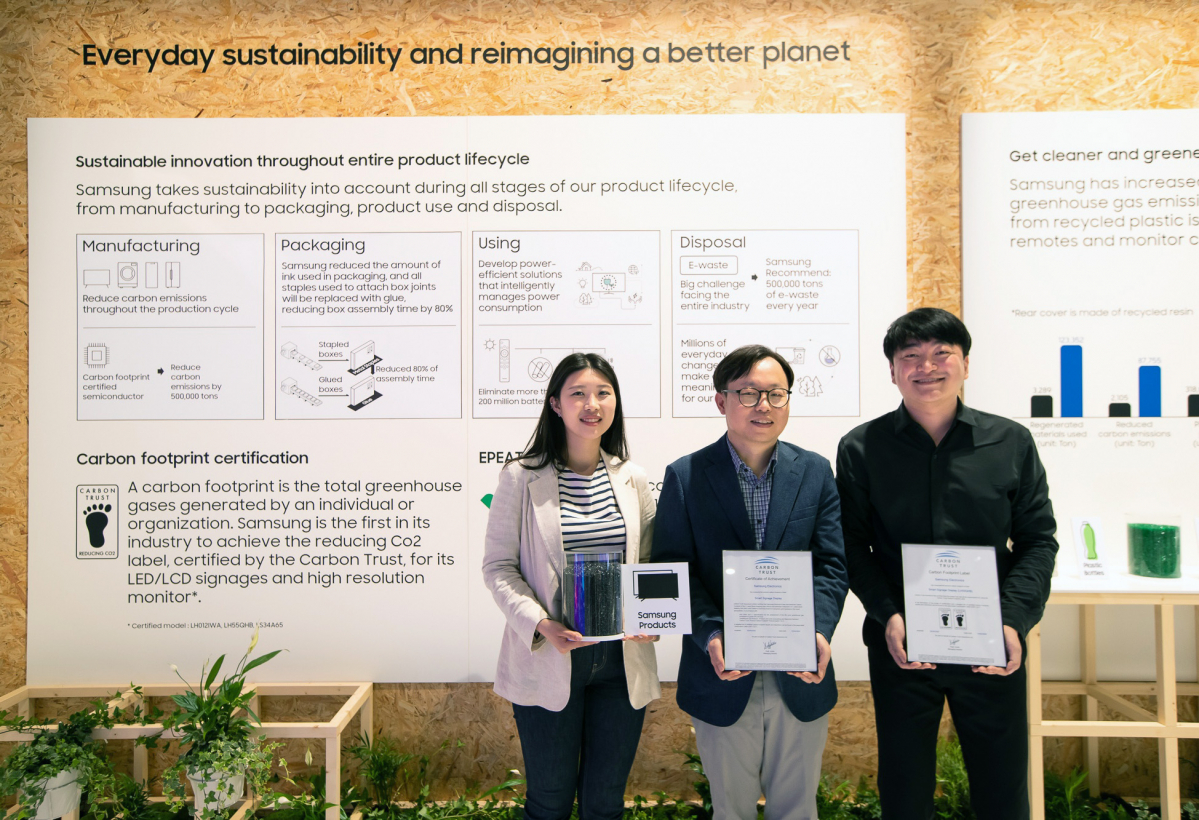 ▲ ISE 2022가 열리고 있는 스페인 바르셀로나 피라 그라 비아 전시장에서 삼성전자 영상디스플레이사업부 Enterprise(엔터프라이즈) 개발 이종포 상무(가운데)와 개발자들이 사이니지 제품 탄소 발자국 인증서와 제품에 활용되는 재생 플라스틱을 들고 있다. (사진제공=삼성전자)