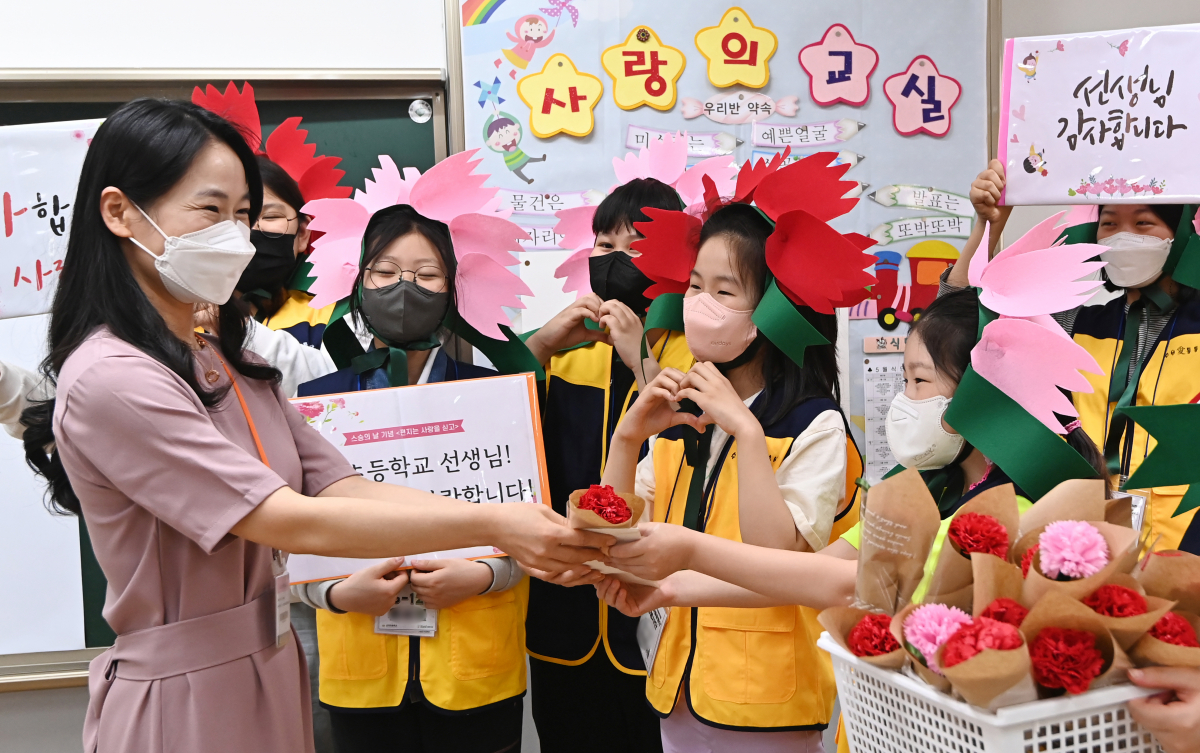 ▲스승의 날을 사흘 앞둔 12일 오후 경기도 수원시 영통구 산의초등학교에서 학생대표들이 선생님에게 직접 만든 카네이션과 감사의 편지를 전달하고 있다.  (뉴시스)