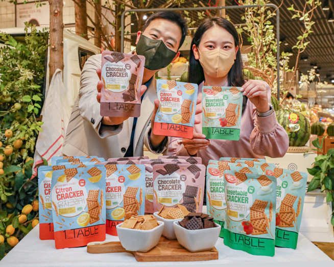 ▲서울 강남구에 위치한 현대백화점 무역센터점 지하 1층에서 직원들이 프리미엄 가정 간편식 '원 테이블(1 TABLE)'의 신제품 '비건 크래커'를 소개하고 있다(사진제공=현대백화점)