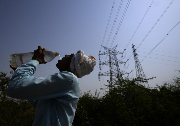 ▲3일(현지시간) 폭염이 덮친 인도 뉴델리에서 한 근로자가 송전선 옆에서 물을 마시고 있다. 뉴델리/AP연합뉴스