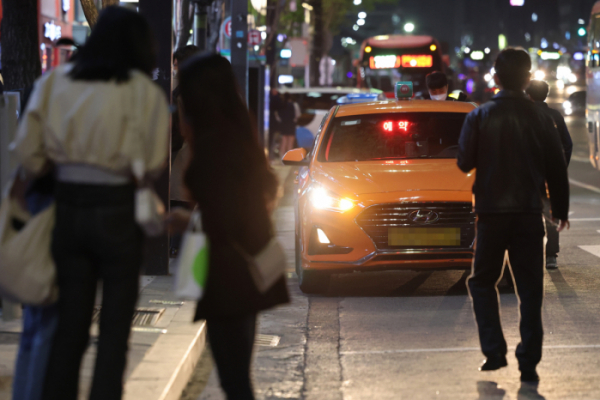 ▲지난달 18일 사회적 거리두기가 전면 해제된 이후 자정을 넘긴 시각에 택시를 잡고 있는 시민들의 모습.  (연합뉴스)