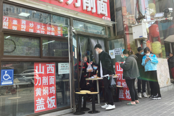 ▲노동절인 1일 중국 수도 베이징 차오양구의 한 음식점 직원이 문 앞에 대기 중인 고객에게 포장 음식을 전달하고 있다. 베이징/로이터연합뉴스