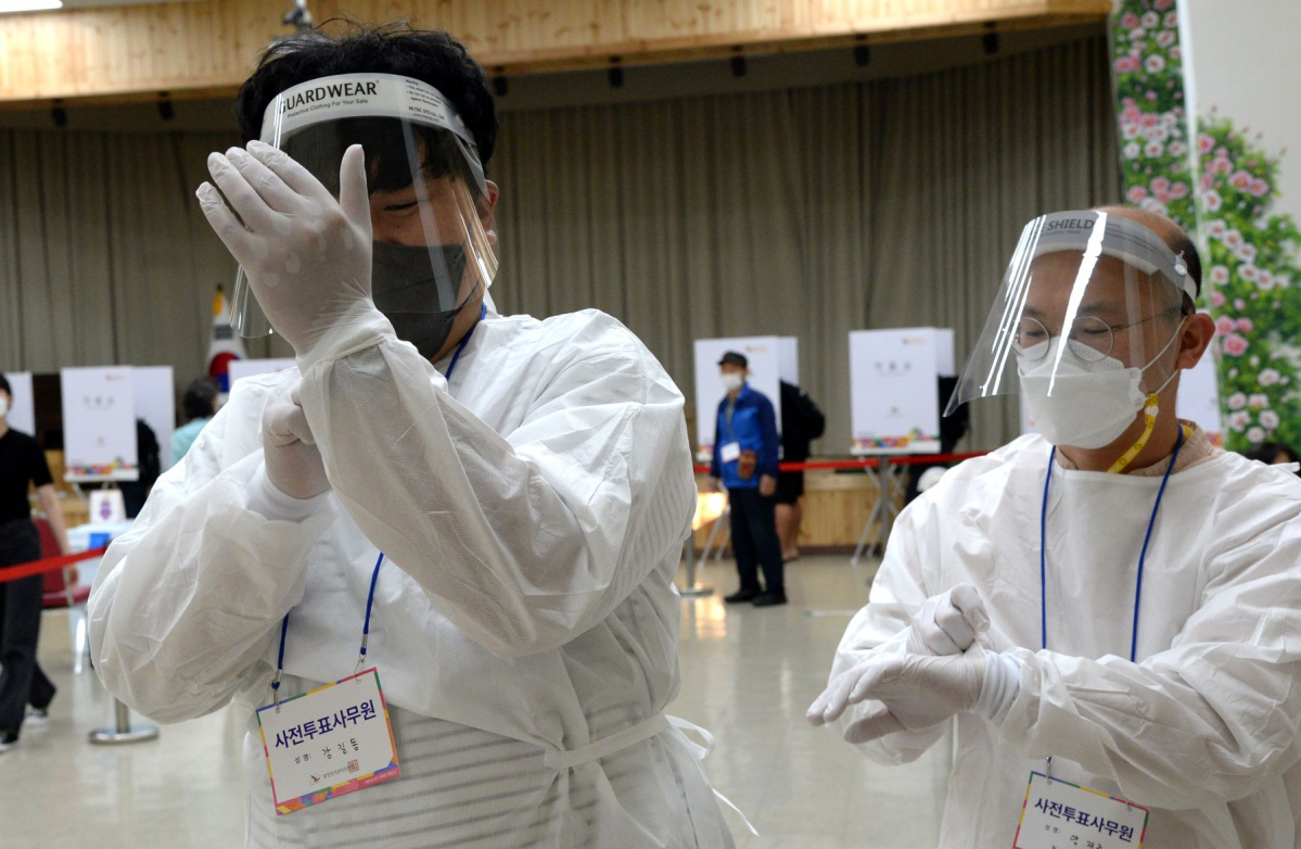 ▲제8회 전국동시지방선거 코로나19 확진자 사전투표를 앞둔 지난달 28일 전북 전주시 전라북도보훈회관 사전투표소에서 투표사무원들이 방호복을 입으며 확진자 투표를 준비하고 있다.  (뉴시스)
