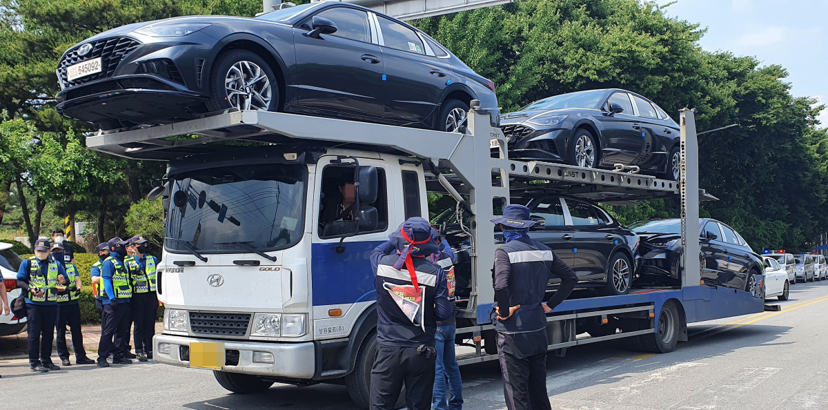 ▲충남 아산 현대차 출고장 앞 도로에서 화물연대 소속 노조원들이 완성차를 싣고 나오는 화물차를 막고 파업 당위성을 설명하고 있다.  (연합뉴스)