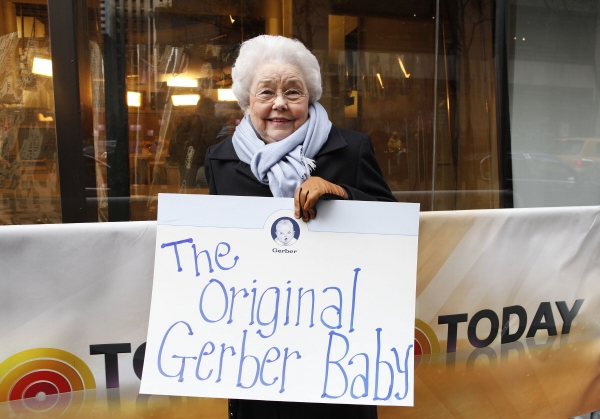 ▲앤 터너 쿡 여사가 2012년 11월 6일(현지시간) 미국 뉴욕에서 개최된 거버의 행사에 앞서 NBC 방송사에서 ‘원조 거버 아기’라는 푯말을 들고 기념사진 촬영을 하고 있다. 뉴욕/AP뉴시스
