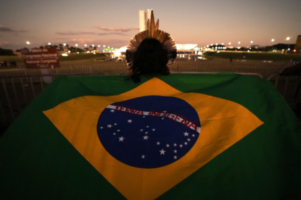 ▲ Um cidadão usa uma bandeira brasileira no ombro em Brasília.  Notícias da AP