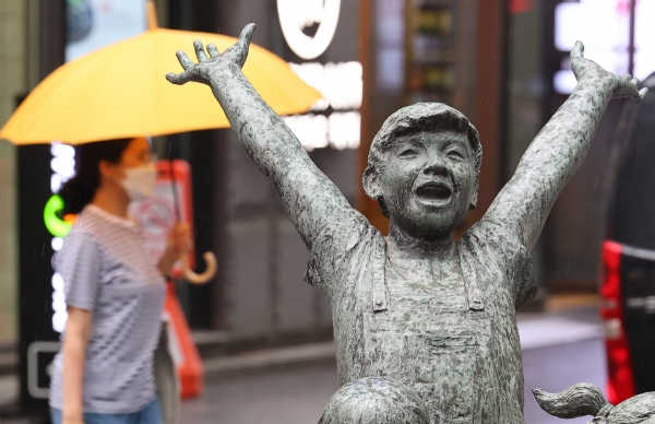 ▲10일 오후 서울 명동 거리에서 우산을 쓴 시민이  동상 뒤를 지나고 있다. (연합뉴스)