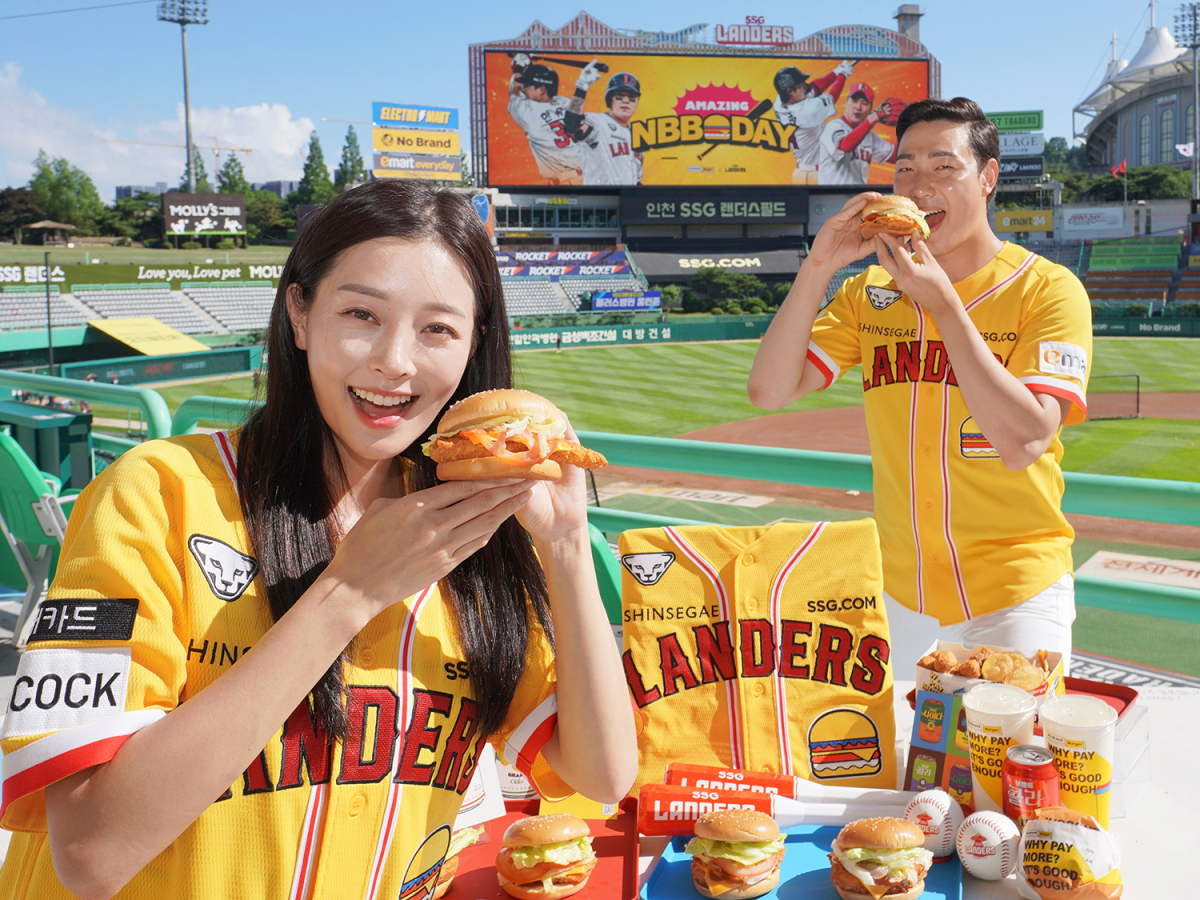 ▲3일 인천 미추홀구 SSG랜더스필드에서 모델들이 신세계푸드가 노브랜드 버거(NBB) 데이를 기념해 특별 제작한 노브랜드 버거 유니폼과 랜더스페셜 버거를 소개하고 있다.  (사진제공=신세계푸드)