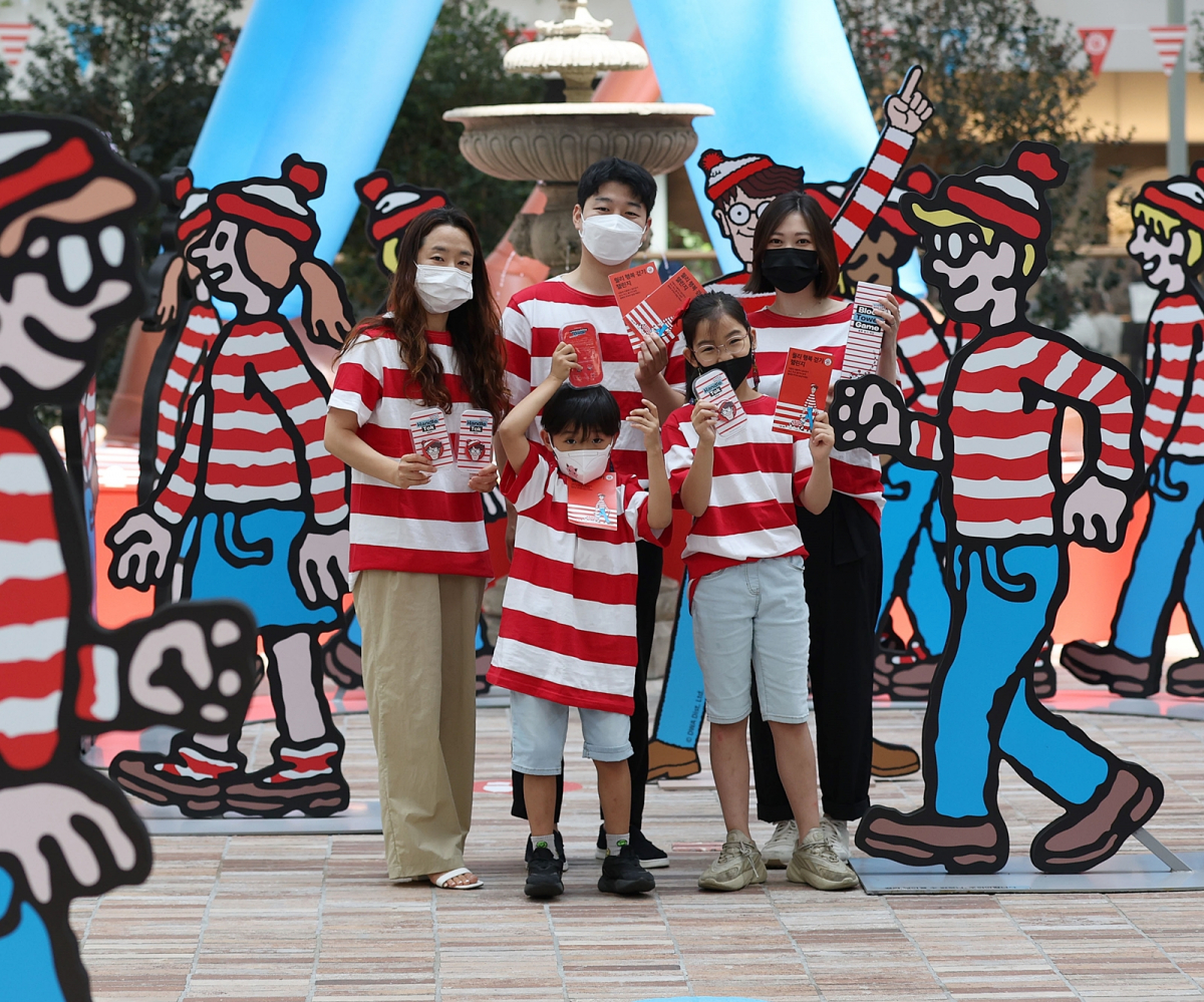 ▲더현대 서울 5층 사운즈 포레스트에서 월리 행복 걷기 챌린지에 참여한 고객들이 한정판 참여 기념품을 선보이고 있다. (사진제공=현대백화점)