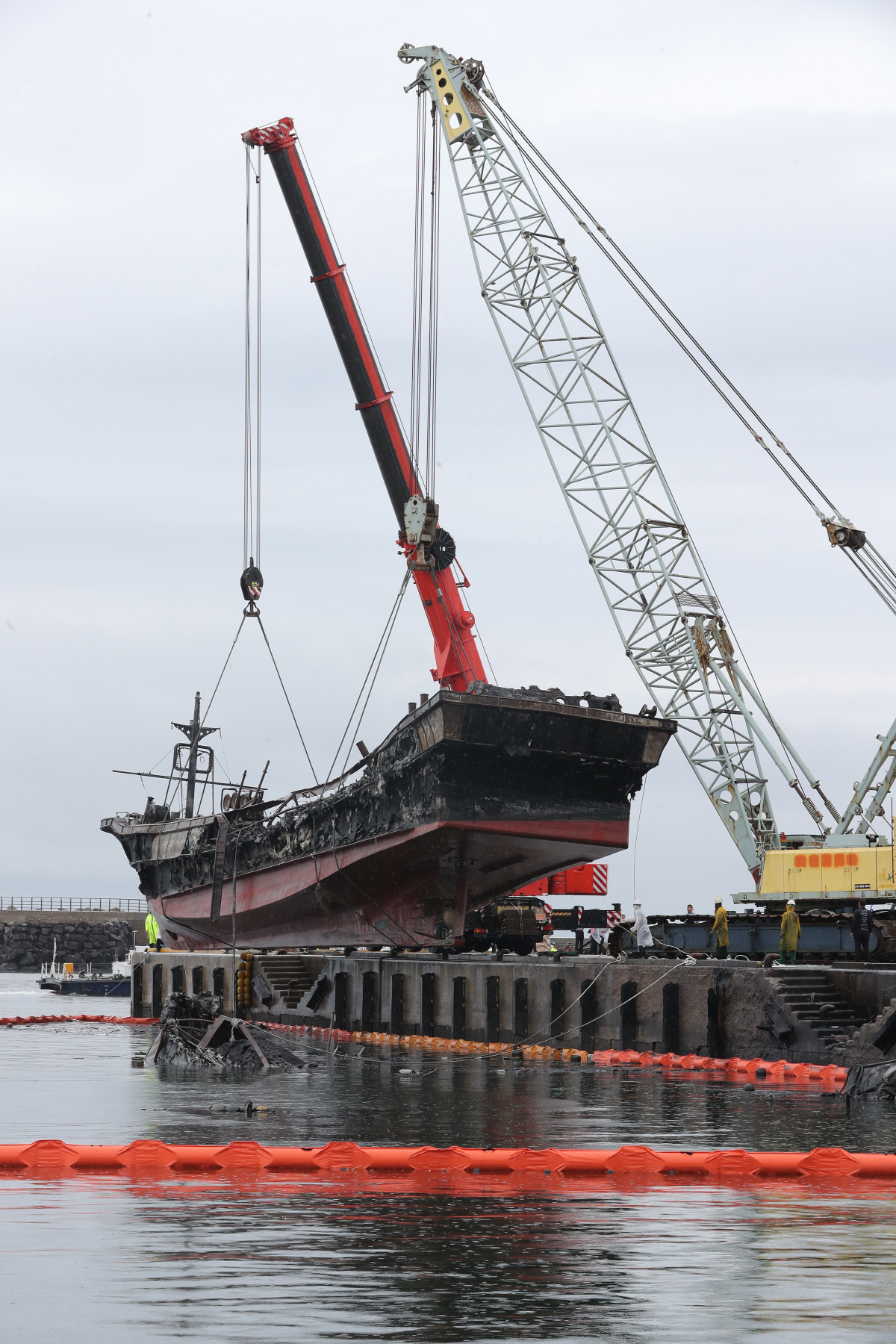 ▲(연합뉴스) 11일 오전 제주시 한림읍 한림항에서 크레인 2대가 화재 선박을 인양하고 있다.
