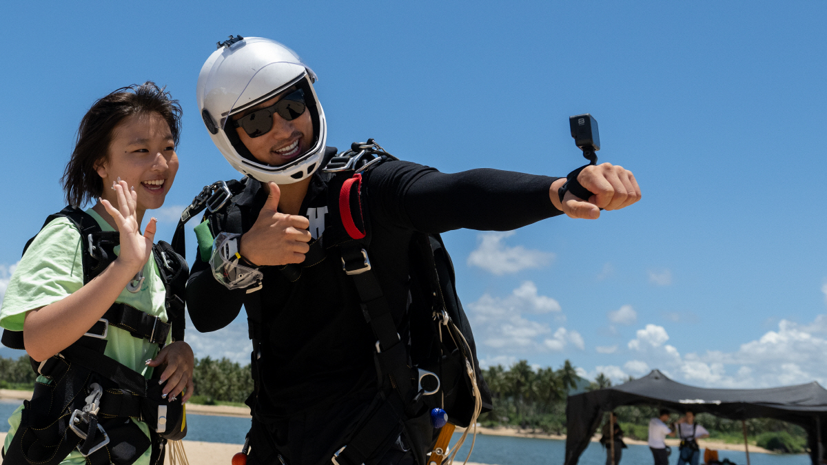 ▲중국 하이난성 싼야에서 지난달 22일 파라슈트 체험자가 전문가와 사진을 찍고 있다. 싼야/신화뉴시스
