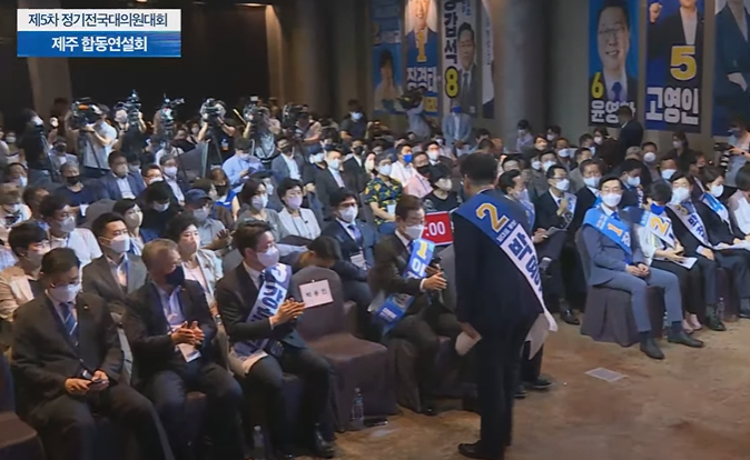 ▲이재명 더불어민주당 당대표 후보는 7일 제주 순회 연설을 마치고 내려온 박용진 후보와 눈을 마주치지 않고 핸드폰을 보며 오른손으로 악수를 했다. (델리민주tv 갈무리)