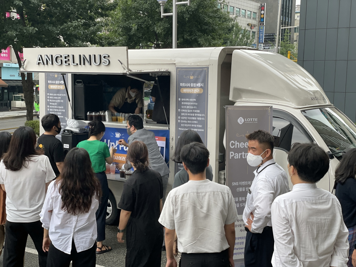 ▲커피 트럭 앞에서 음료를 받기 위해 줄서 있는 파트너사 직원들. (롯데백화점)