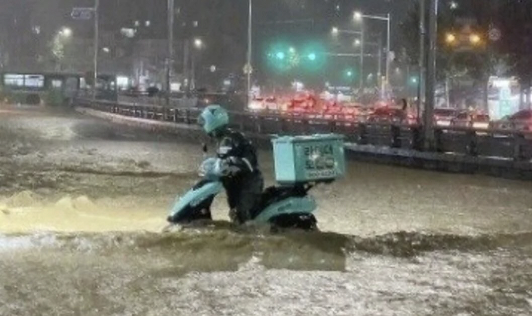 ▲8일 침수된 도로 위에서 배달원이 오토바이를 끌고 가고 있다. (출처=온라인 커뮤니티 캡처)