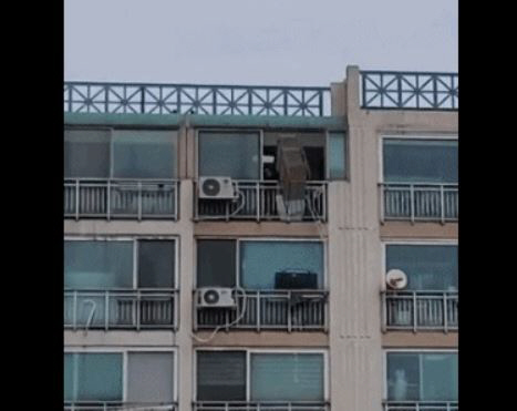 ▲A 씨가 9층 아파트 베란다 밖으로 물건을 던지고 있다. (출처=온라인 커뮤니티)
