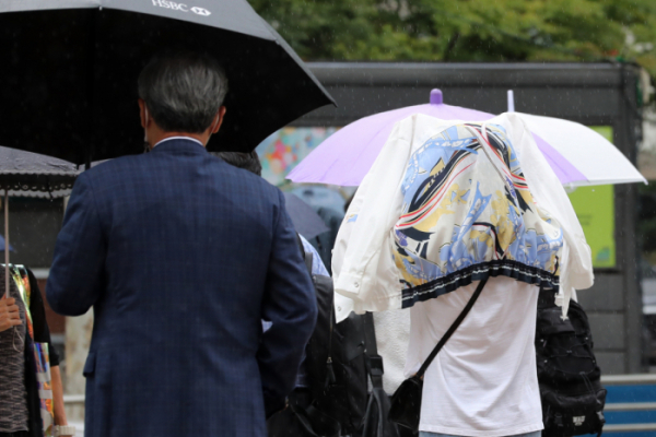 ▲우산이 없는 한 시민이 옷으로 비를 막으며 걸어가고 있다.  (뉴시스)