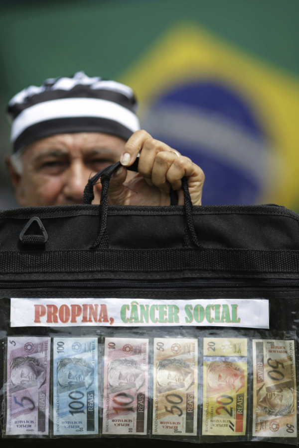 ▲브라질 브라질리아에서 열린 시위에 참여한 한 남성이 브라질 화폐 헤알(Real) 지폐를 들어보이고 있다. 브라질리아/AP뉴시스