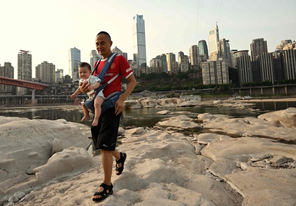 ▲중국 충칭시의 양쯔강 지류인 자링강이 25일 가뭄으로 바닥을 드러낸 가운데 한 아버지가 아이를 안고 걷고 있다. 충칭/AFP연합뉴스  
