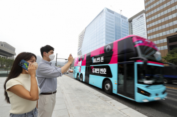 ▲KT 고객이 ‘듀얼번호 버스’를 촬영해 SNS 올리는 인증샷 이벤트에 참여하는 모습. (사진제공=KT)