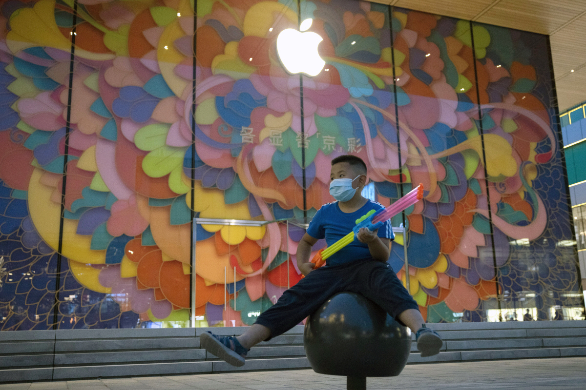▲중국 베이징에 있는 애플스토어 앞에서 한 어린이가 마스크를 착용한채 물총을 들고 앉아 있다. 베이징/AP뉴시스