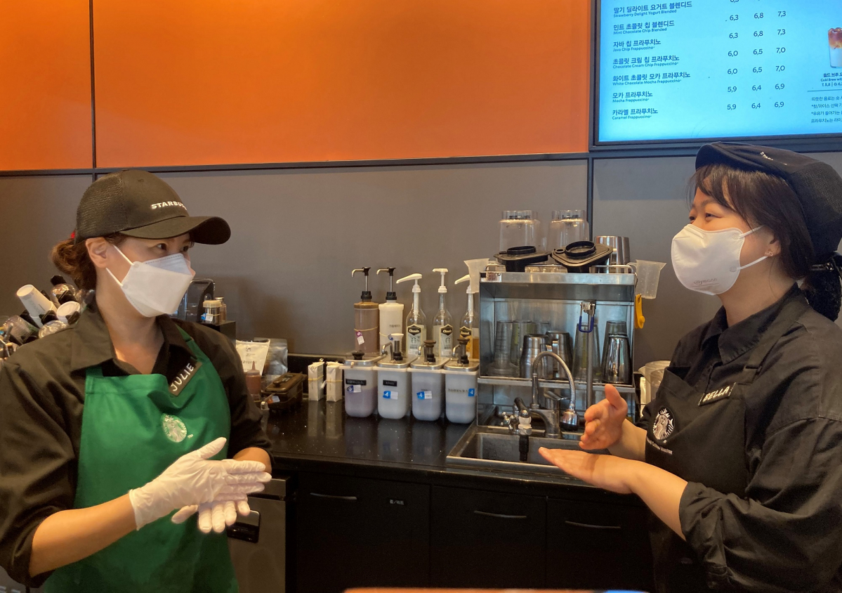 ▲올해 하반기 장애인 바리스타로 입사한 김정희 바리스타(왼쪽)가 동료 파트너와 수어로 대화를 나누고 있다. (사진제공=스타벅스코리아)
