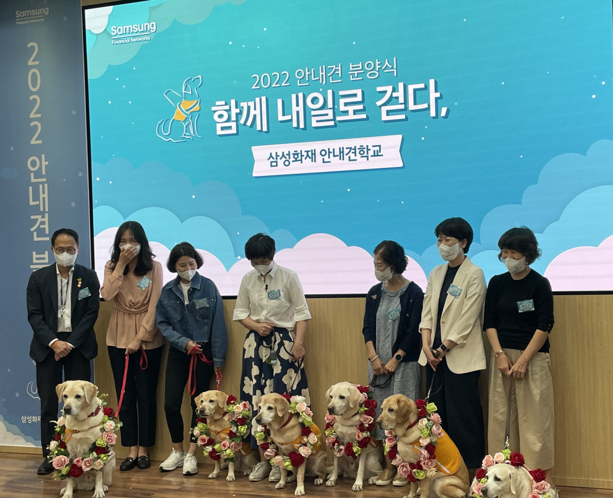 ▲20일 열린 '함께 내일로 걷다,' 행사에서 몽실, 태양, 탄이, 아랑이, 티나, 훈민 등 6마리의 은퇴 안내견들이 꽃목걸이를 걸고 기념촬영을 하고 있다. 왼쪽 끝은 박주민 더불어민주당 의원.  (강태우 기자 burning@)