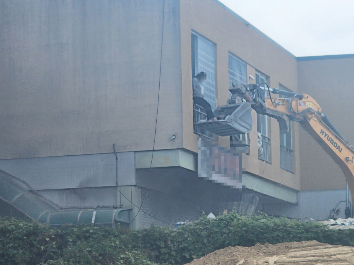 ▲24일 오후 2시께 대전 유성구 복용동 한 자동차 관련 업체에서 불이 났다. 인근 건설업체 직원들이 이 불로 집 안에 고립됐던 40대 여성과 두 살배기 아기를 굴착기를 동원해 구조하고 있다. (연합뉴스)