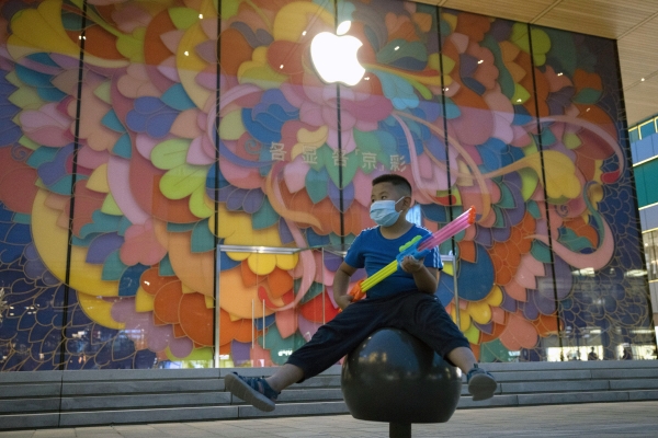 ▲중국 베이징에 있는 애플스토어 앞에서 한 어린이가 마스크를 착용한채 물총을 들고 앉아 있다. 베이징/AP뉴시스
