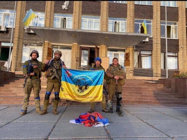 ▲우크라이나군이 10일(현지시간) 쿠피안스크 시청 청사 앞에서 국기를 들고 있다. 출처 올레 니콜렌코 트위터.
