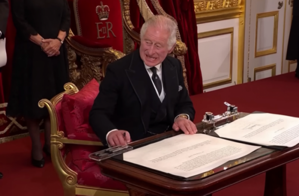 ▲찰스 3세 영국 국왕이 10일(현지시간) 런던성 제임스 궁전에서 열린 국왕 즉위식에서 서명하기 전 책상 위 물건을 치우라는 듯 손짓하고 있다. 출처 가디언 유튜브 영상 캡처