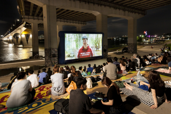 ▲한강무비나잇 프로그램을 통해 한강변에서 영화를 보고 있는 시민들. (자료제공=서울시)