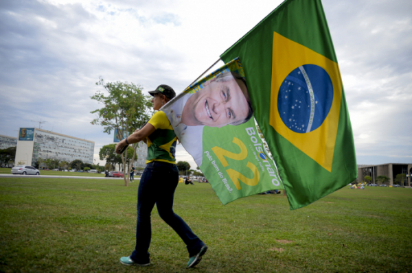 ▲2일(현지시간) 브라질 브라질리아에서 대통령 선거 1차 투표가 마감된 가운데 한 여성이 자이르 보우소나루 대통령의 사진과 브라질 국기를 들고 걸어가고 있다. 브라질리아/AP뉴시스