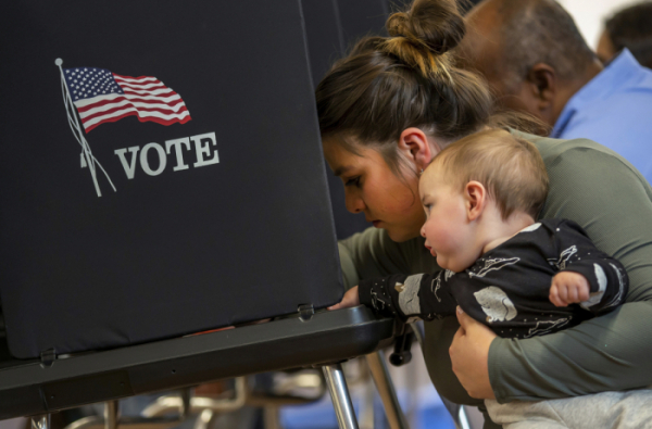 ▲앨버커키=AP/뉴시스] 미국 중간 선거일인 8일(현지시간) 뉴멕시코주 앨버커키의 한 투표소에서 한 여성이 생후 11개월 된 아들을 안고 투표하고 있다.