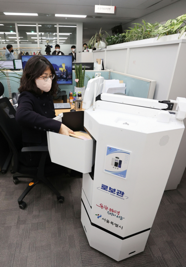 ▲22일 서울시청에서 직원이 로봇 공무원 '로봇관'이 배달한 문서를 꺼내고 있다.  (연합뉴스)