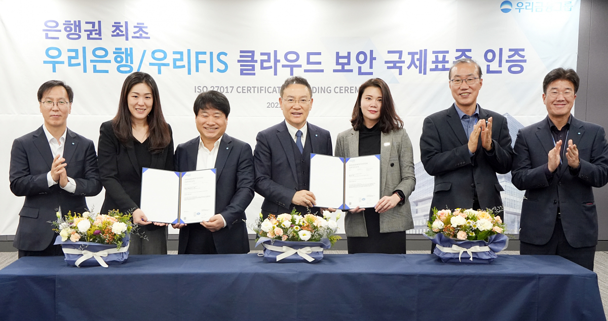 ▲고정현 우리은행 IT그룹 부행장 겸 우리에프아이에스 대표(왼쪽서 네 번째), 김백수 우리은행 정보보호그룹 부행장(왼쪽서 세번째), 이소영 DNV BA 코리아 대표(왼쪽서 두 번째)가 6일 마포구 우리에프아이에스 본점에서 'ISO 27017 국제표준 클라우드 보안인증 수여식'에서 기념촬영을 하고 있다. (사진제공=우리금융그룹)