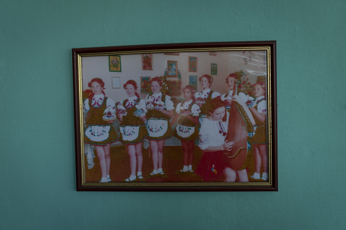 ▲지난달 15일(현지시간) 러시아가 퇴각한 우크라이나 남부 헤르손 외곽의 한 학교 벽에 우크라이나 전통 의상을 입은 학생들의 모습이 담긴 사진이 걸려 있다. 키셀리브카/AP뉴시스
