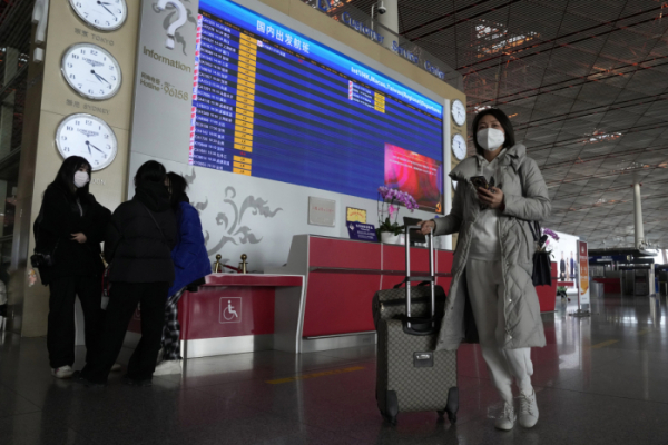 ▲중국 베이징 국제공항 터미널에서 13일 한 탑승객이 항공편 출발 정보를 공지하는 게시판 앞을 지나가고 있다. 베이징/AP뉴시스