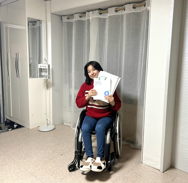 ▲제주도에 사는 지체장애인 곽현주씨가 굿닥 소개 책자를 들고 있다. (사진제공=굿닥)