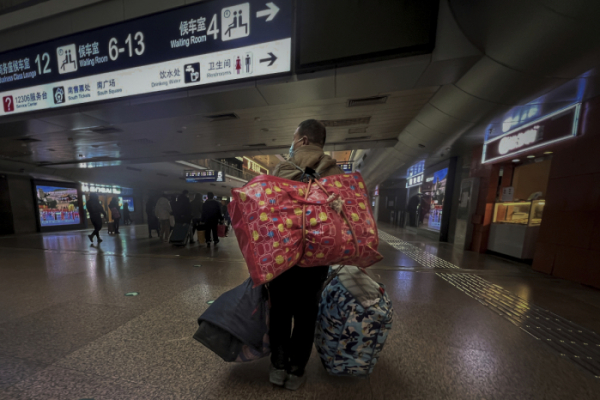 ▲중국 베이징의 기차역에 6일(현지시간) 이주 노동자가 마스크를 착용하고 짐을 메고 기차를 타러 가고 있다. 베이징/AP뉴시스