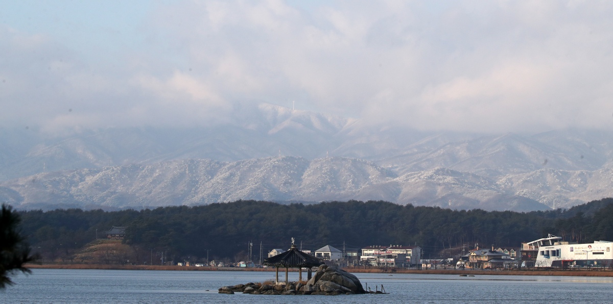 ▲14일 밤사이 내린 눈으로 강릉시 경포호 너머로 멀리 보이는 백두대간이 흰 눈에 덮여 장관을 연출하고 있다. 연합뉴스