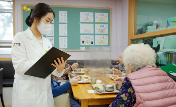 ▲아워홈 영양사가 서울 마포구에 있는 한서데이케어센터에서 '인지기능개선 관리 식단'을 시설 이용 어르신에게 소개하고 있다. (사진제공=아워홈)